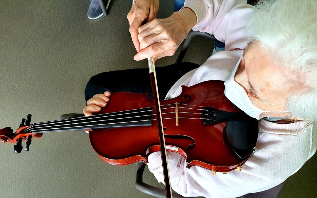 Photo illustrant une patiente s'essayant au violon appartenant à l'orchestre national de toulouse dans le cadre du programme d'activités de la clinique des minimes